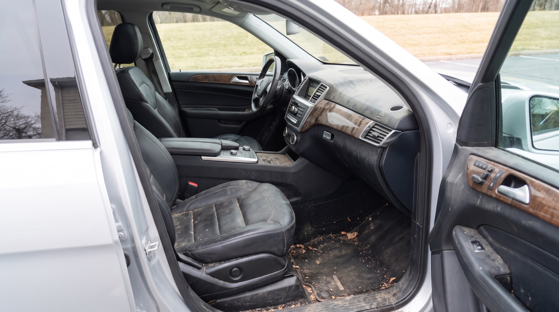 Before: SUV front cabin with dusty dashboard, stained leather seats and mud on the floor mats