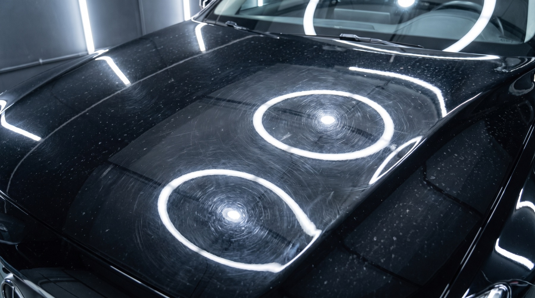 Before: black car bonnet covered in swirl marks, water spots and a hazy clear coat