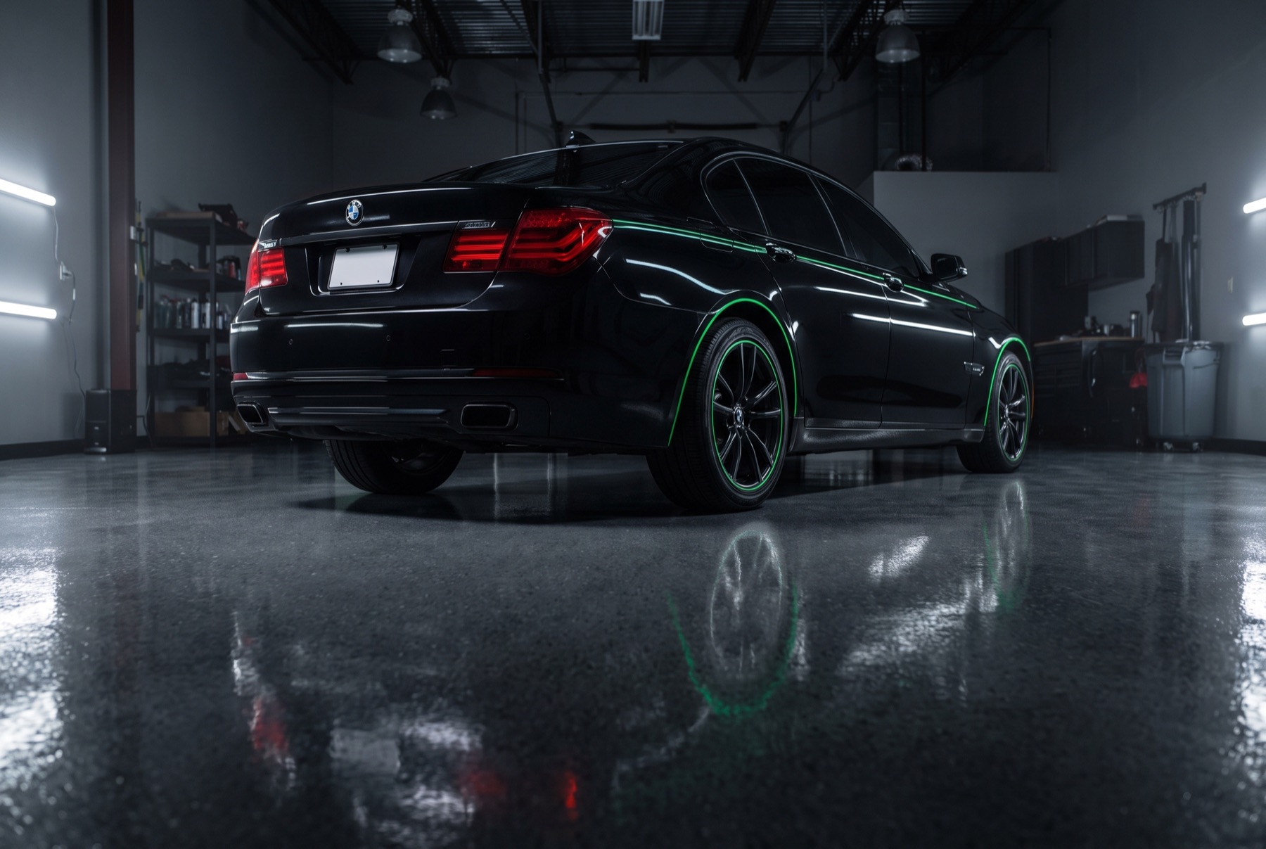 Rear three-quarter view of a black saloon with green rim lighting in a detailing studio