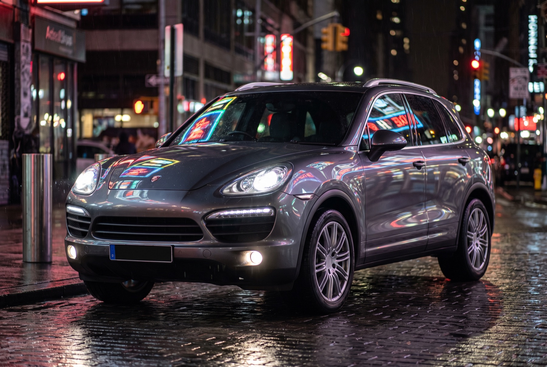 Glossy grey SUV reflecting city lights on a wet street at night