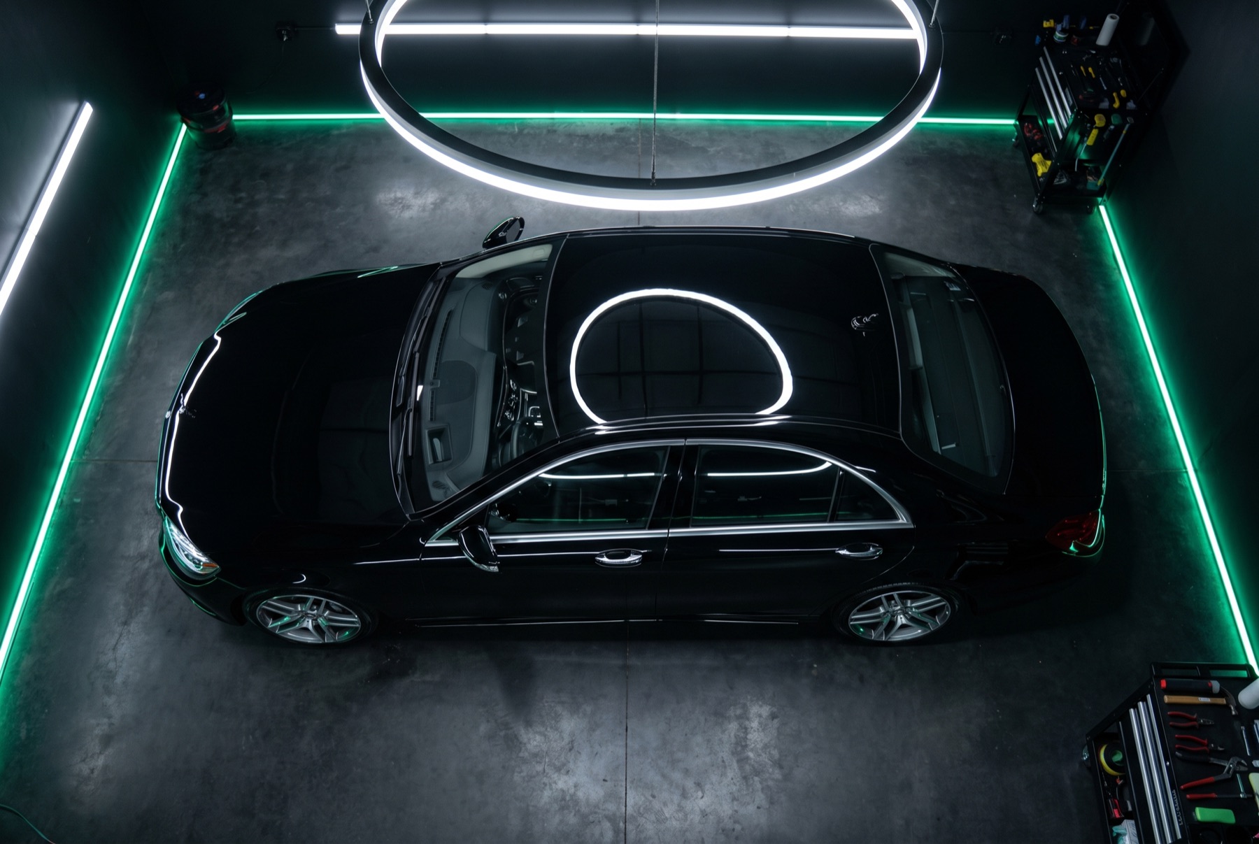 Overhead view of a glossy black saloon under a circular studio ring light